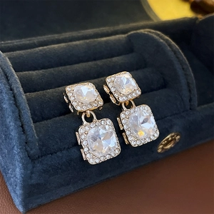 Macro detail of square crystal flower earrings in a velvet jewelry box