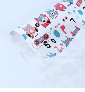 Detailed view of rolled cartoon gift wrap with pink monsters and vintage radio motifs