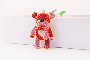 Close-up of colorful rhinestone bear keychain with gold base on a white box edge