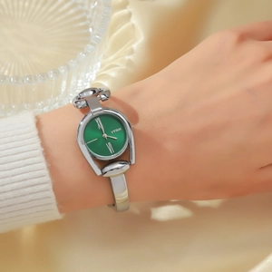 Close-up of vintage emerald green dial watch with silver metal bangle strap on silk