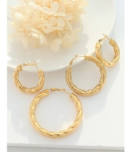 Three sizes of French vintage twisted gold hoop earrings on elegant white ceramic display