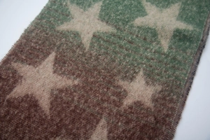 Close-up of fluffy bouclé yarn scarf featuring star patterns and green-brown gradient