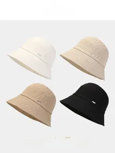 Detail of four colors of sun hats with wrinkled fabric texture and small metal logo