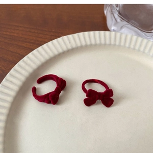 Detail of red velvet bow hair accessories on a cream ceramic plate with vintage vibes
