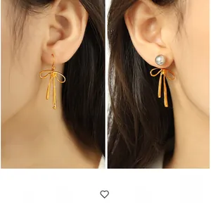 Detail showing golden bow-knot earrings with grey pearls and fluid metal texture