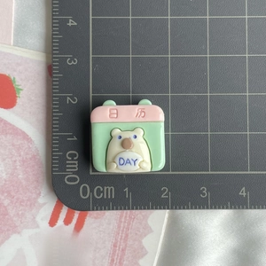 Detail of pink and green resin calendar charm for DIY accessories on a cutting mat