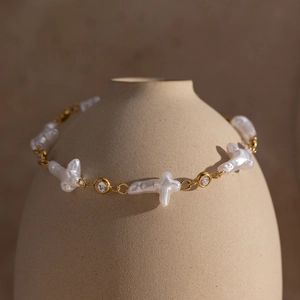 Dettaglio del bracciale in acciaio inossidabile 18K con croce di perle barocche e zircone