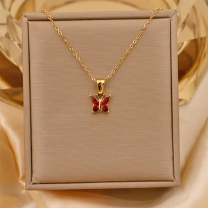 Detail of 18K gold plated butterfly pendant with red zircon inlay on a jewelry box