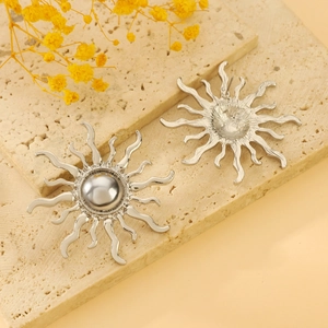 Detail of sun-shaped earrings with silver pearls on a beige stone display tray