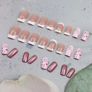 French tip press-on nails set with pearls, rhinestones, and pink heart designs