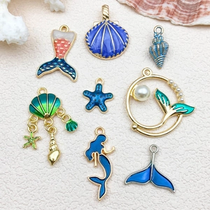 Set of 8 gold ocean themed enamel charms featuring blue mermaids, shells and starfish