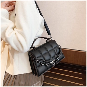 Detail of black quilted faux leather handbag with chunky chain strap and top handle