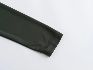 Macro detail of dark green dress cuff showing fine stitching and smooth knit texture