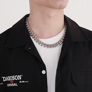 Detail of silver Cuban chain necklace worn by a model against a white background