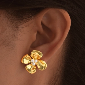 Detailed view of elegant gold flower earrings with three white pearls worn by a model