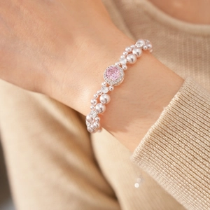 Primo piano di un bracciale di perle a due fili con zircone rosa sul polso di una modella