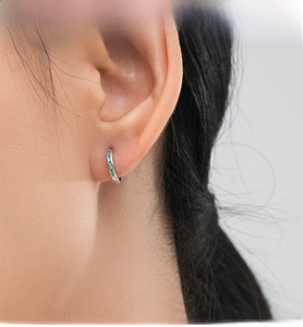 Close-up of S925 silver hoop earrings featuring emerald-cut green cubic zirconia stones