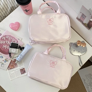 Beauty case in raso rosa con ricamo Lucky 1 e fiocco su un tavolo da trucco bianco