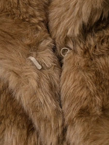 Close-up of the metal hook closure and thick brown faux fur texture on the coat