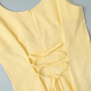 Vue détaillée du dos d'une robe jaune clair avec fermeture éclair et lacets croisés