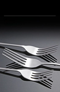 Macro shot of three polished stainless steel forks with smooth rounded tines on black background