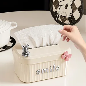 Cream-style tissue box with silver bear figurine and smile letter decoration