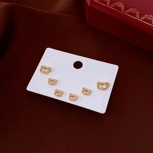 Detailed view of six golden bear stud earrings with white zircons on a white card display