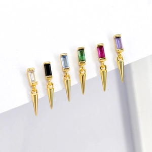 Macro view of six colorful rectangular zircons with gold cone pendants on white surface