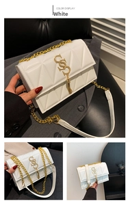 Detail of white quilted chain bag featuring gold S-logo and fringe tassel charm