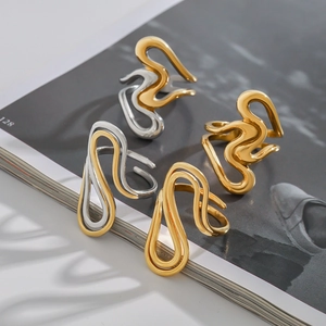 Abstract wavy titanium steel rings in gold and silver finish shown on magazine