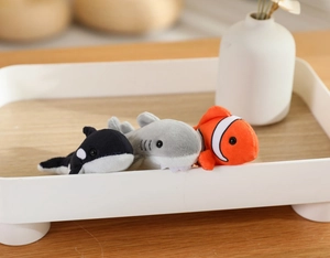 Close-up of plush marine animals including orca, shark, and clownfish on a white tray