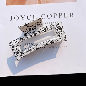 Detailed view of square hollow hair claw clip with black and white ink splash pattern