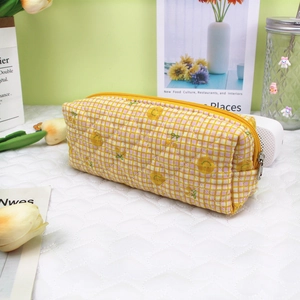 Detail of yellow and pink quilted embroidery pencil case with cute floral and smiley pattern