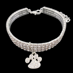 Close-up of three-row crystal pet collar with silver paw print pendant on black background