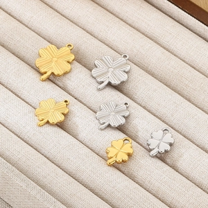 Detail view of gold and silver four-leaf clover stainless steel pendants on a jewelry tray