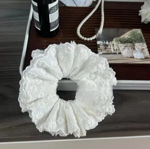 Detail of white 3D floral lace scrunchie with four layers of scalloped edge embroidery