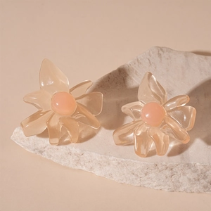 Close-up of translucent resin flower earrings with peach bead center on white stone