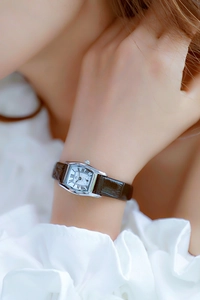 Elegant rectangular silver watch with white Roman dial and brown leather strap on wrist