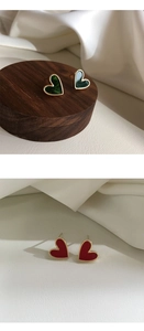 Detailed close-up of dark green and burgundy enamel heart earrings with gold metal borders