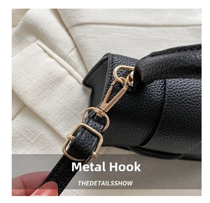 Detail of high-quality gold metal hook and textured black lychee leather bag finish