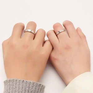 Detailed view of silver couple rings with ECG heart rate pattern worn on fingers