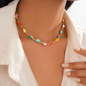 Detail of colorful oval resin stones on a gold chain necklace worn over a white shirt