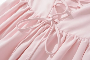 Détail de la robe rose montrant le laçage croisé au dos et la texture en mousseline