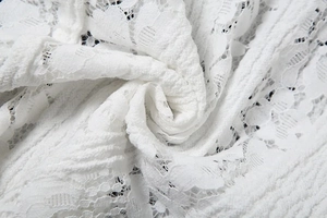 Detailed macro shot of white floral lace fabric with intricate hollow embroidery texture