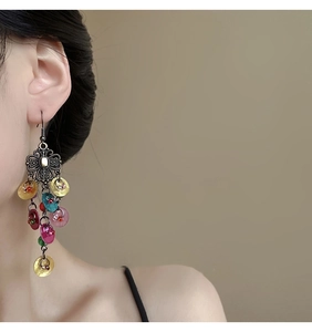 Detail of vintage bohemian shell tassel earrings with multicolored sequins and floral metal