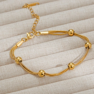 Detail of 18k gold plated stainless steel triple snake chain bracelet with smooth beads