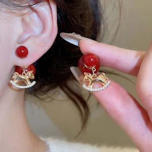 Detail of red bead earrings with 18K gold horse pendant and sparkling zircon accents