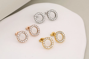 Three pairs of crystal round stud earrings in silver, rose gold, and gold on a tray