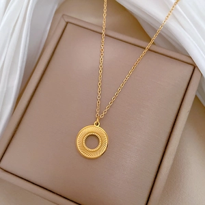 Detailed shot of golden spinning ring necklace on premium beige jewelry box