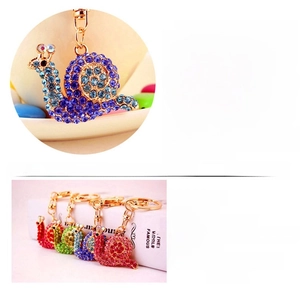 Detail view showing colorful rhinestones and gold plating on the snail keychain